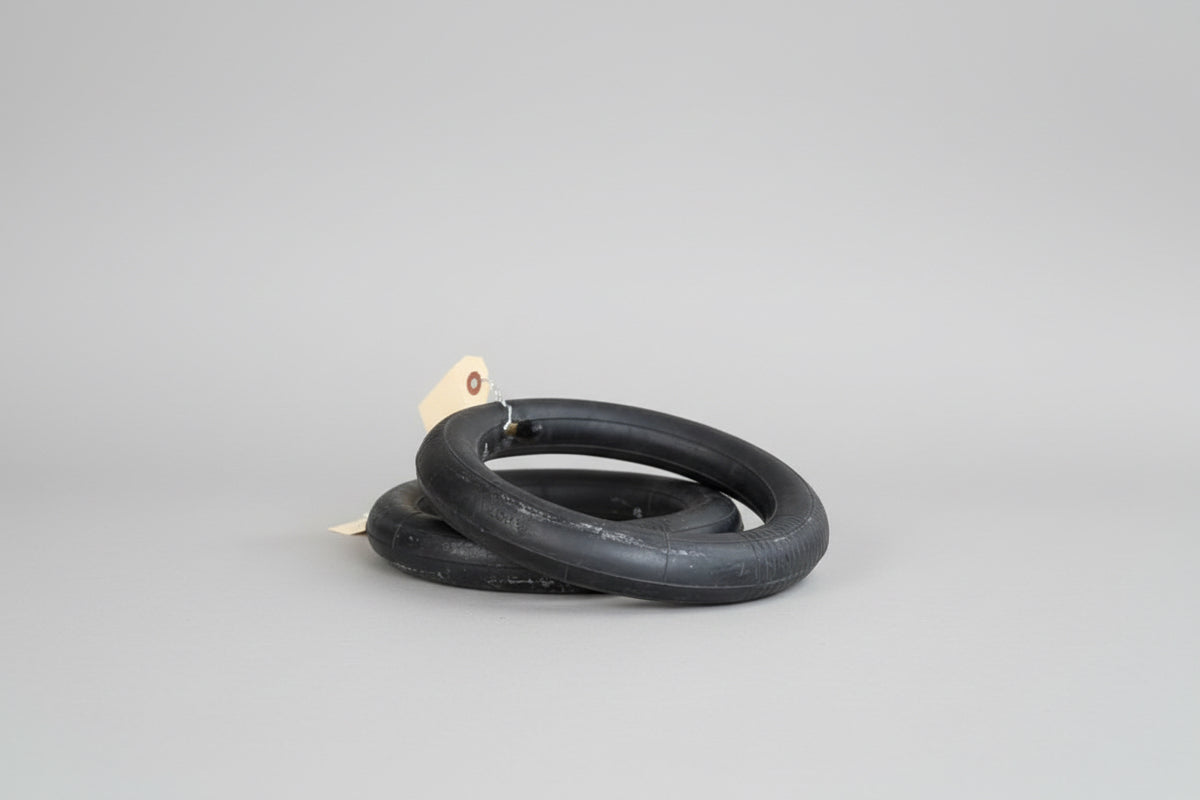 Two black inner tubes on a concrete surface with a brick wall in the background